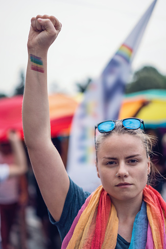 Female showing rainbow tattoo with her fist clenched high up