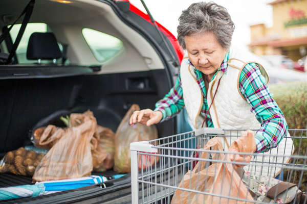 An elderly woman packs her groceries